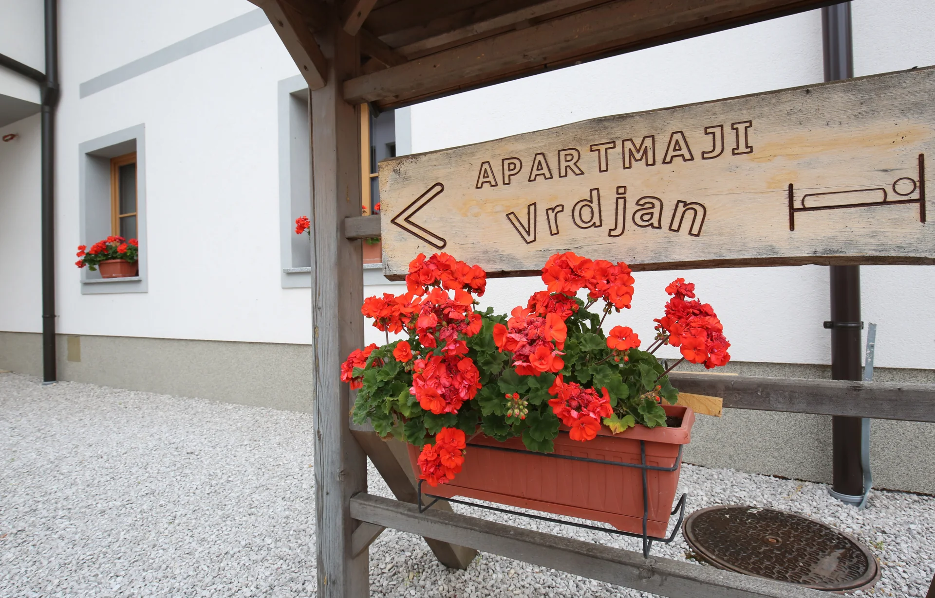 Lesen kažipot Apartmaji Vrdjan z geranijami pred hišo